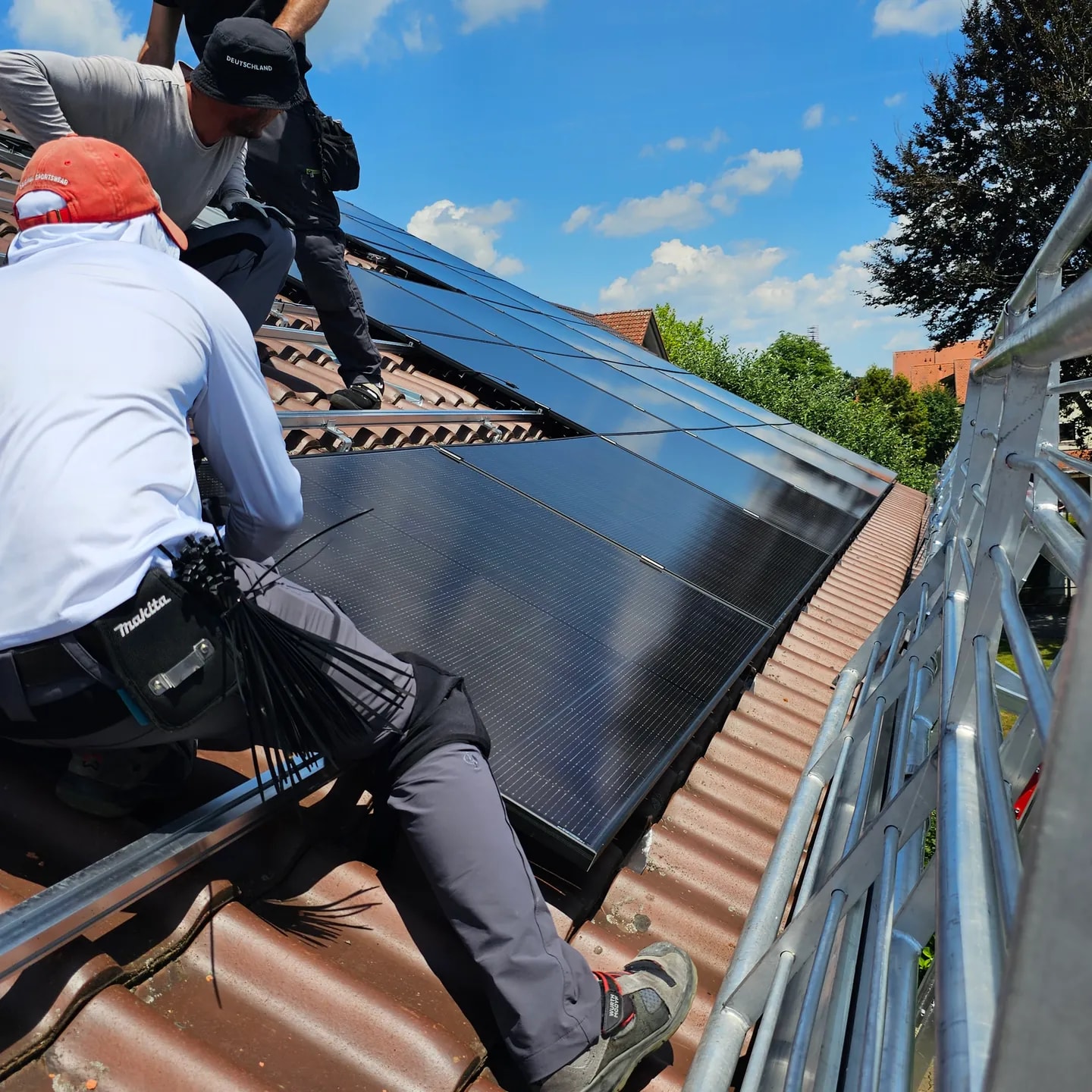 SüdEnergie-Monteure installieren schwarze Photovoltaikmodule auf einem Ziegeldach